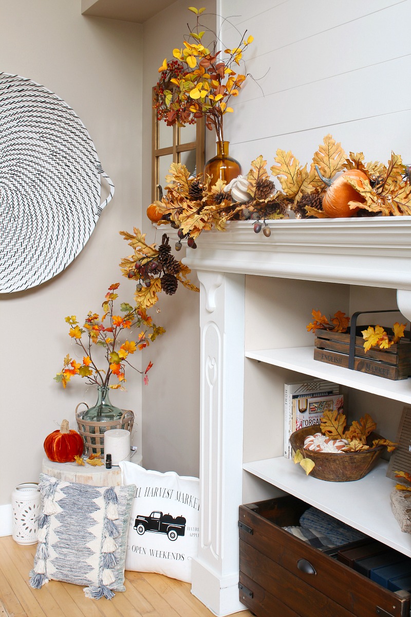 Pretty fall mantel decor ideas with golden oak leaves, pinecones, pumpkins, and amber glass.