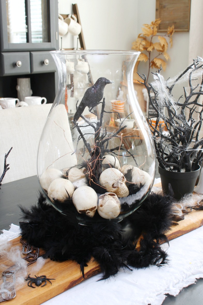 Halloween centerpiece with hurricane lantern and skulls.