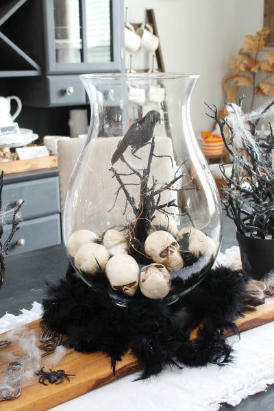 Halloween centerpiece with hurricane lantern and skulls.