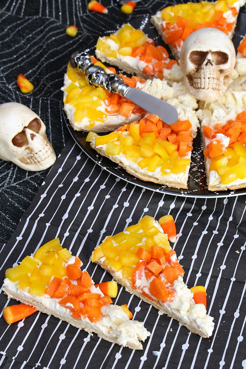 Candy corn Halloween veggie pizza on a Halloween tablecloth.