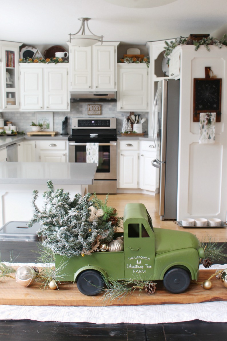Modern farmhouse style white kitchen decorated for Cristmas with greens and whites and dried oranges for a pop of color.