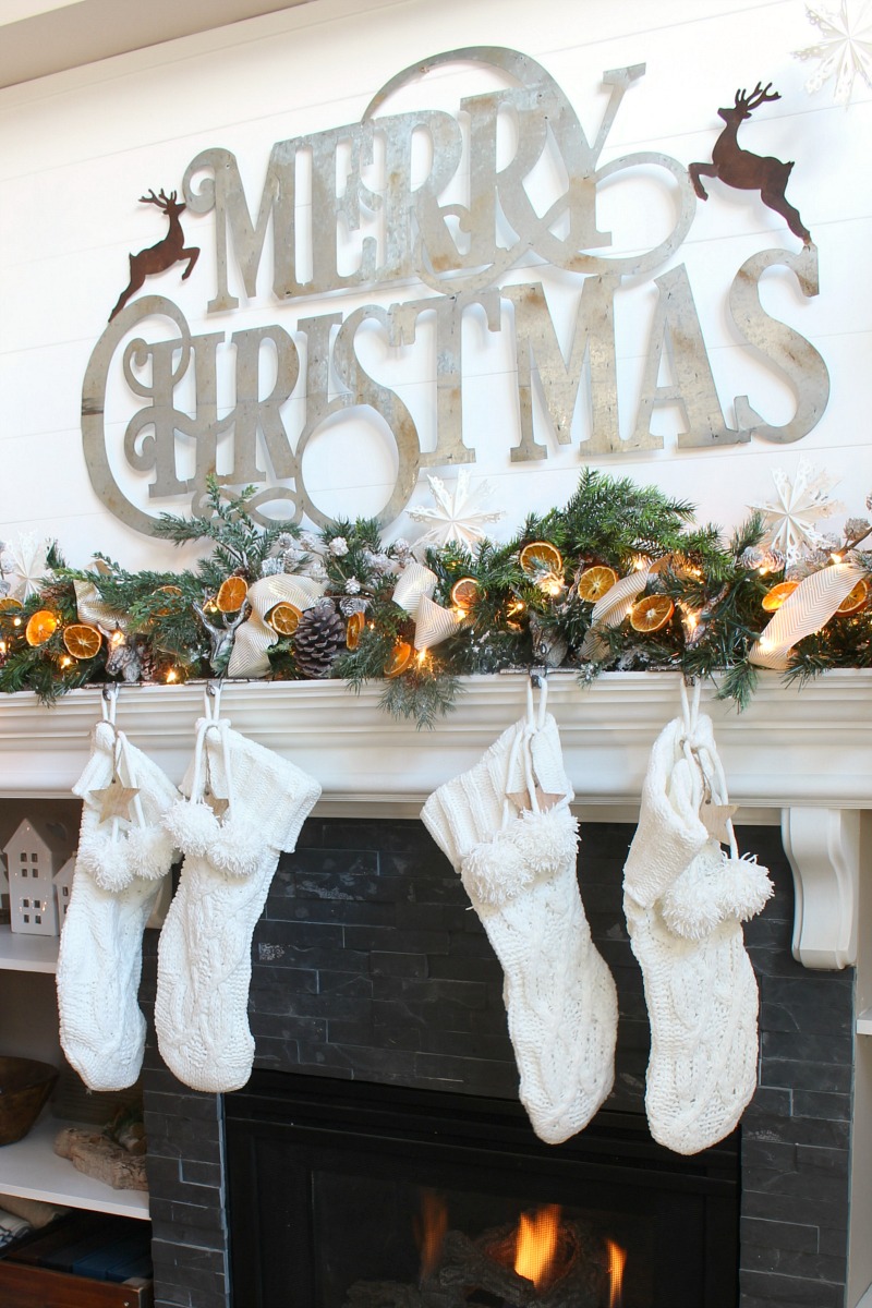 Beautiful Christmas mantel decor with greenery and dried oranges.