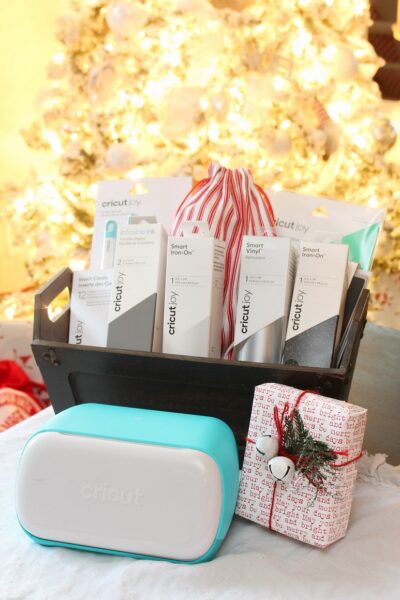 Cricut Joy and Cricut Joy gift basket in front of a glowing Christmas tree.