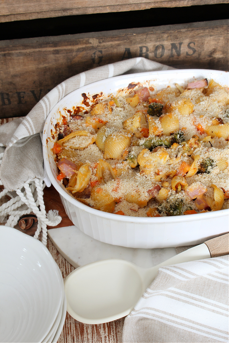 Cheesy vegetable and ham casserole in a baking dish.
