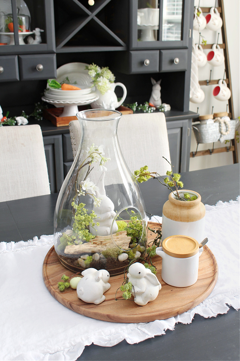 Easter centerpiece with glass terrarium and white bunnies.