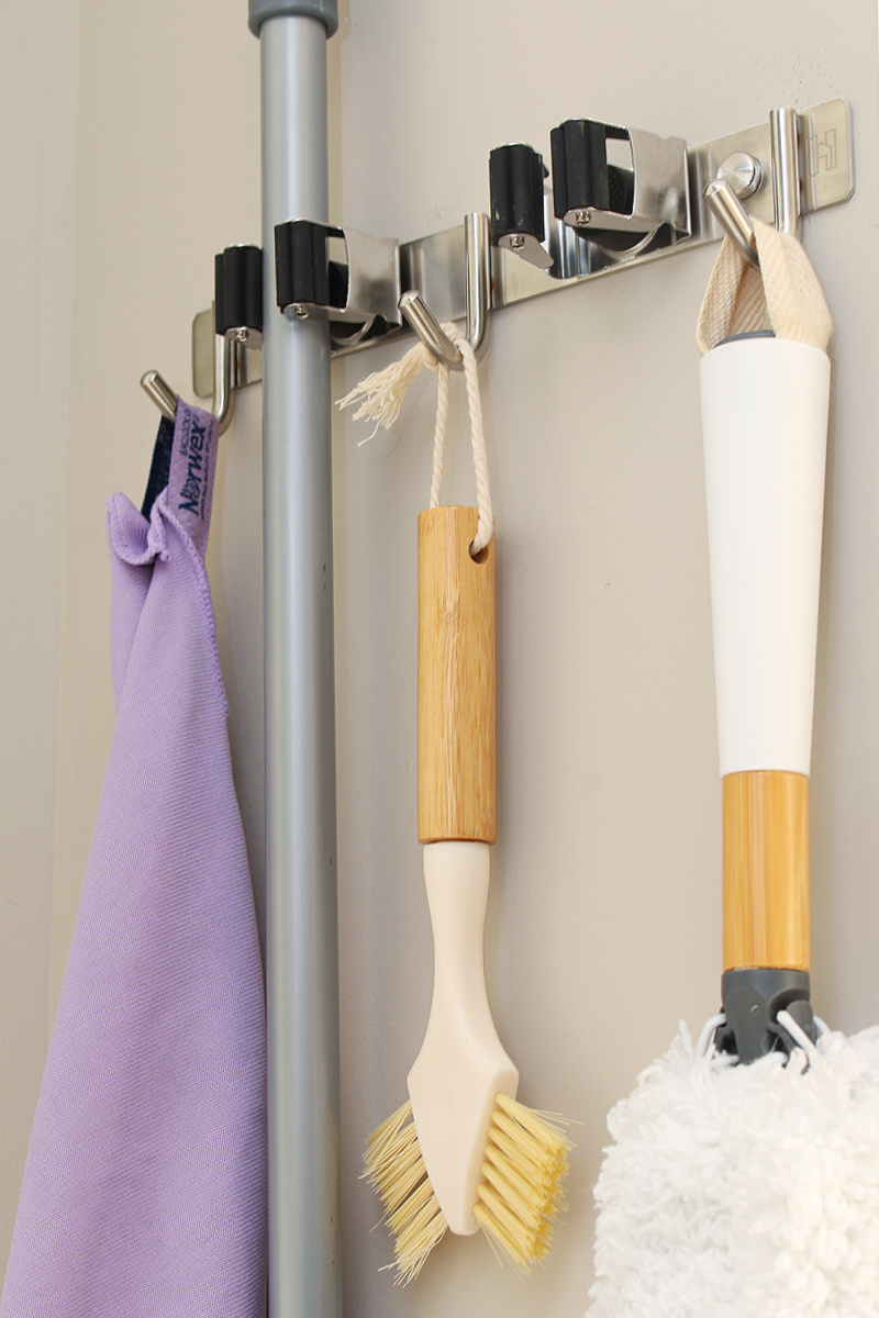 Mop and broom wall holder with hooks for cleaning supplies.