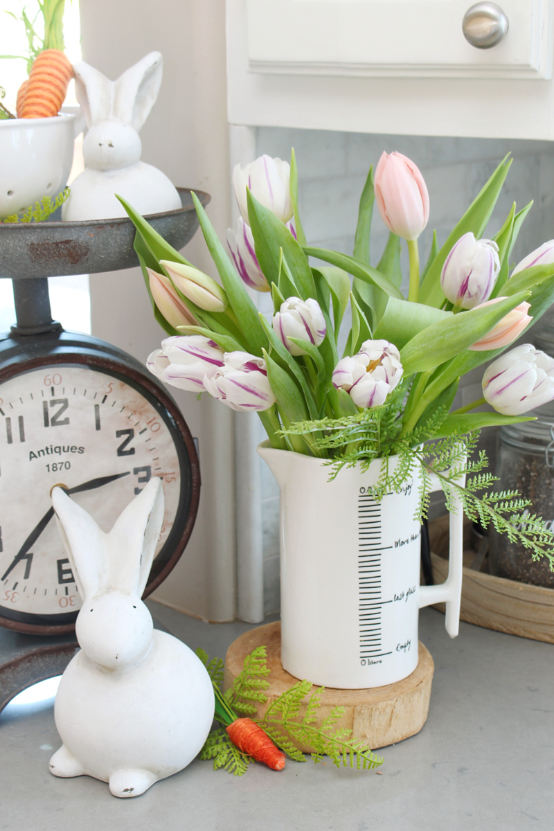 Pretty spring tulips in a white kitchen pitcher with a white bunny.