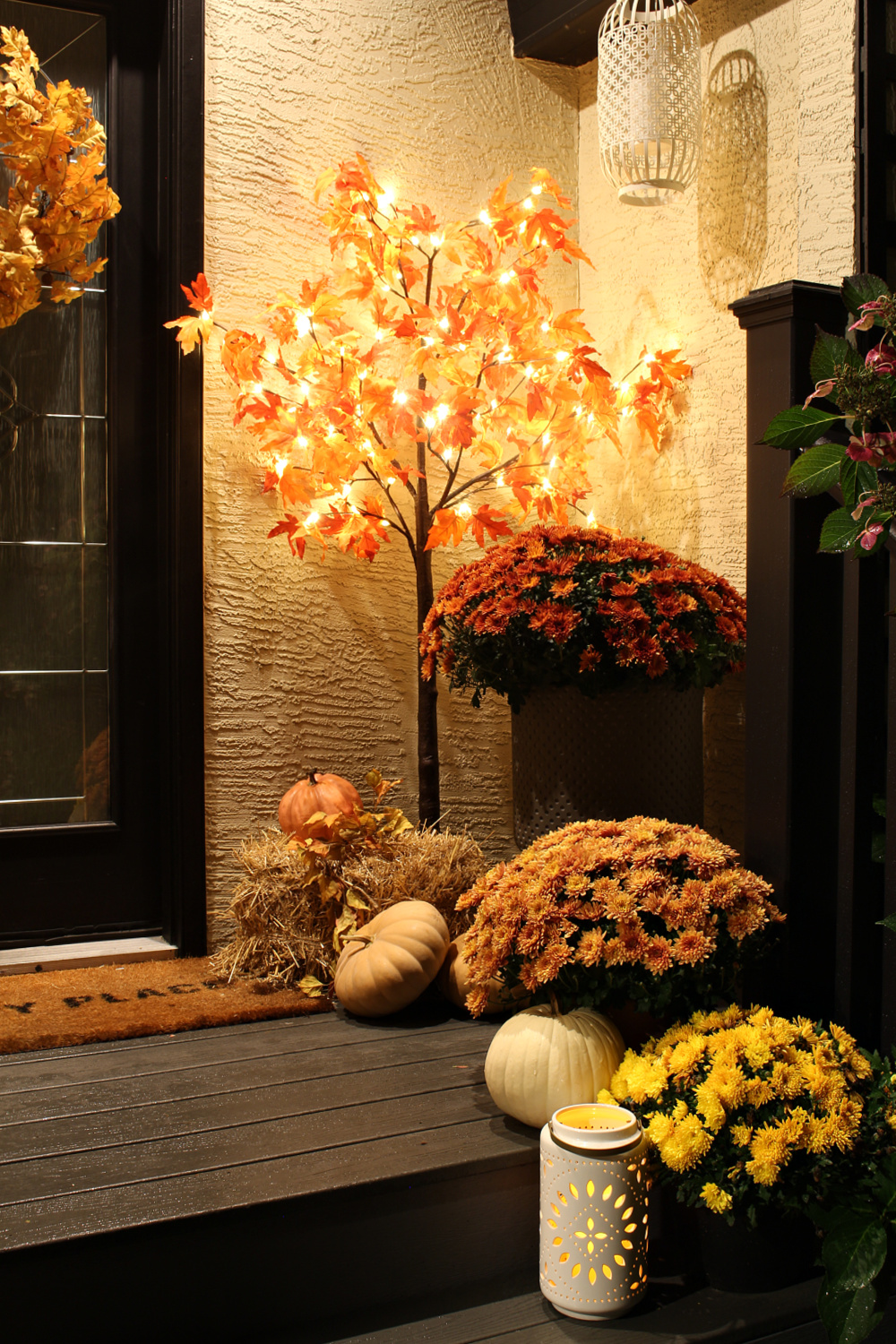 Glowing fall front porch at night with a lighted fall tree and candles.