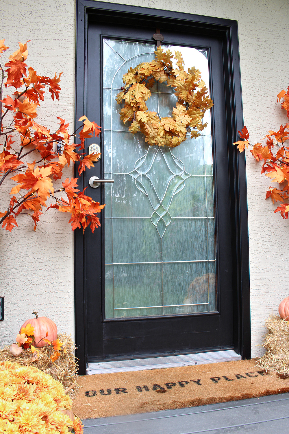 Fall front porch decorated with mums, pumpkins and lighted trees.