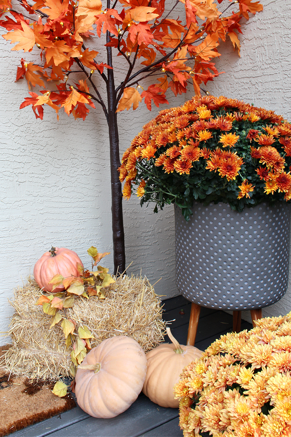 Fall front porch with mums, pumpkins, and hay.