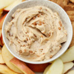 Cream cheese apple dip on a plate with apples and graham crackers.