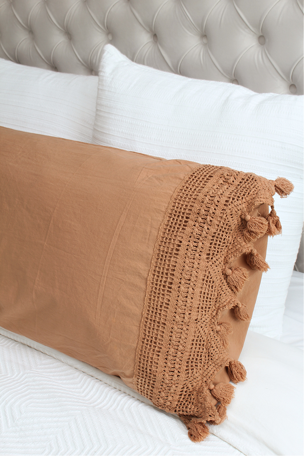 Decorative fall pillows on a bed with white bedding.