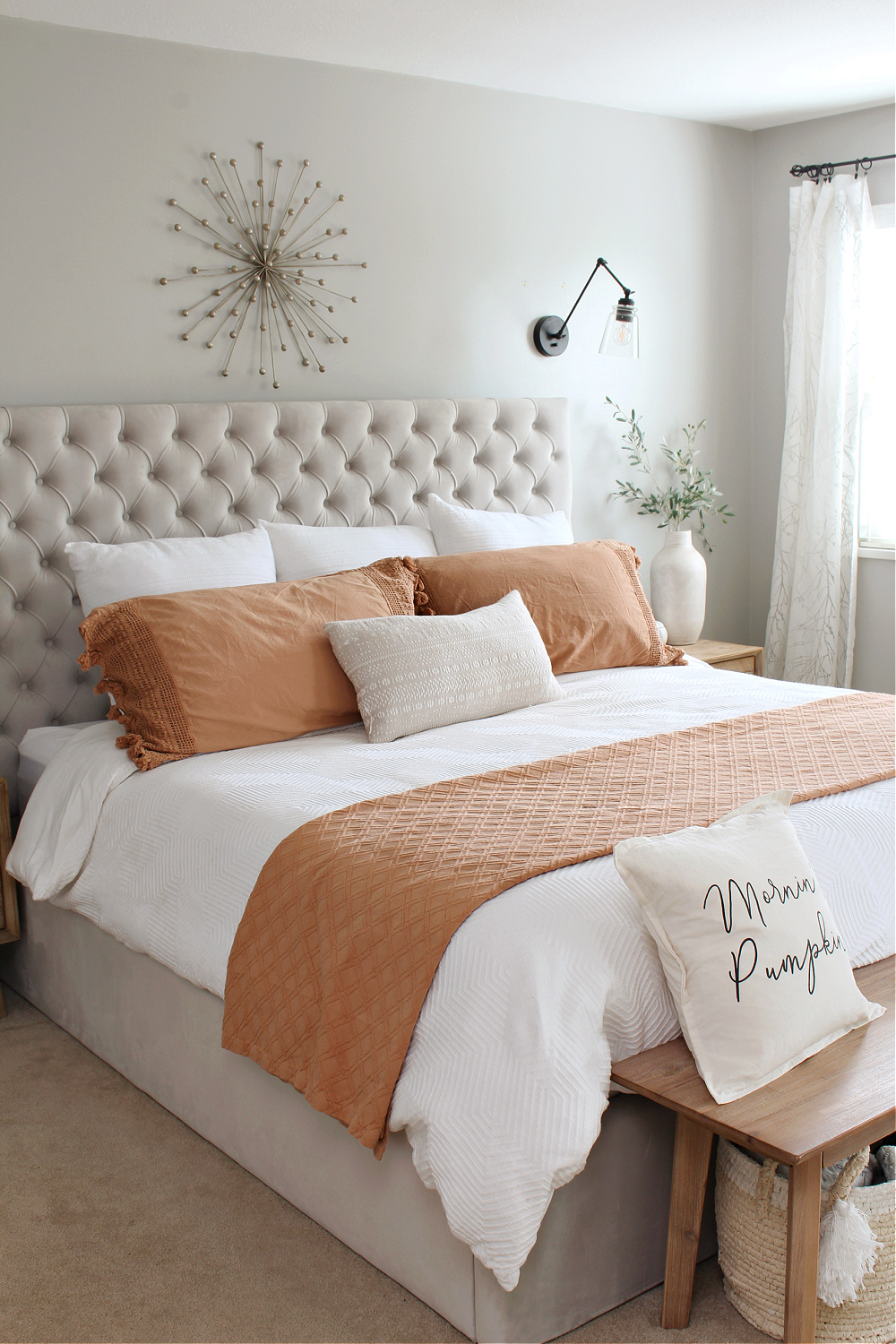 Upholstered bed dressed up for fall with a white duvet and terra cotta quilt and shams.