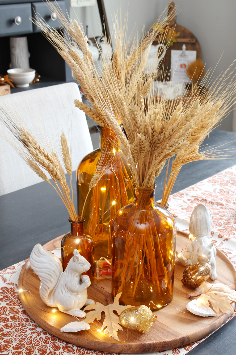 Autumn centerpiece in amber glass and wheat.