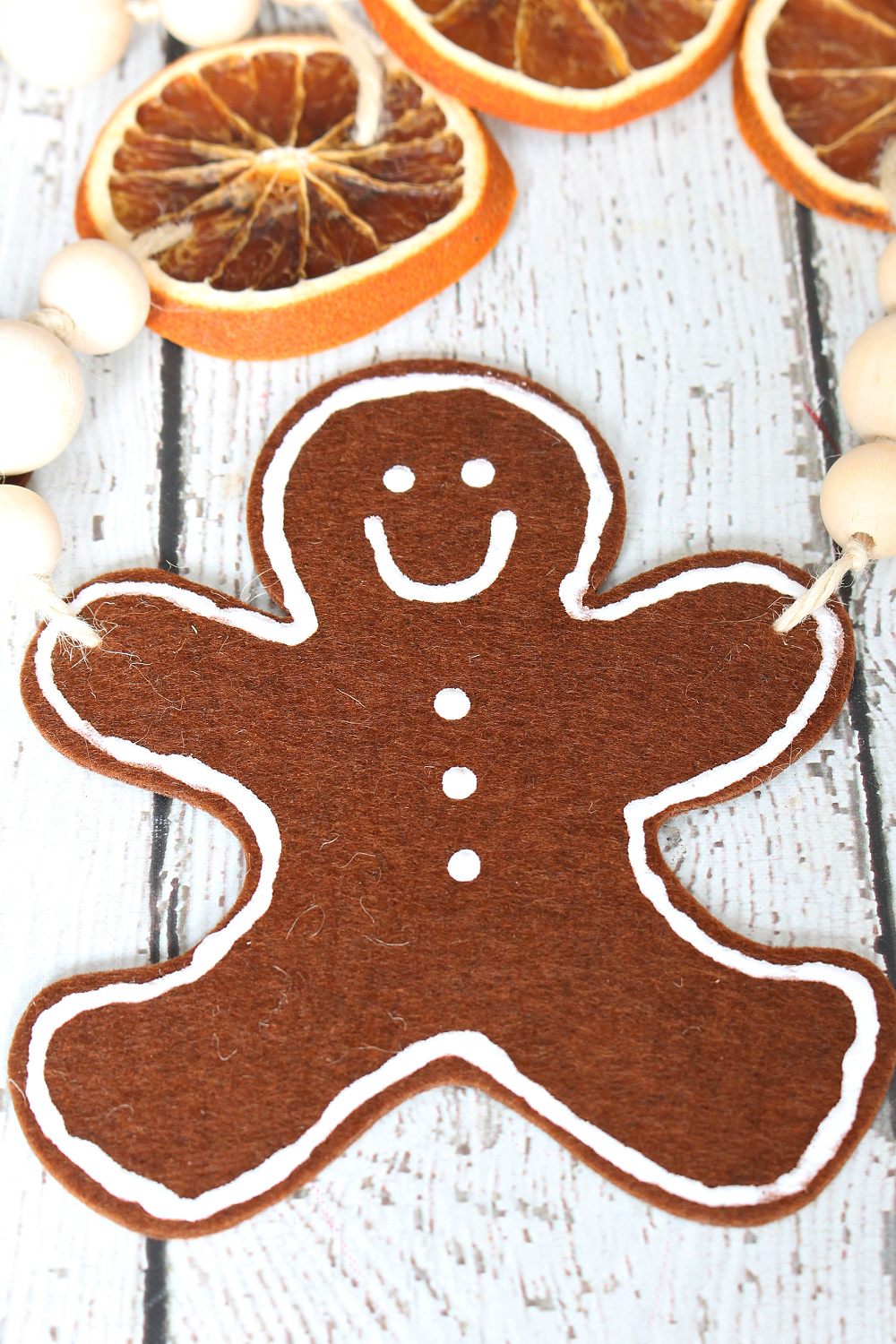 Cute DIY felt gingerbread man garland with dried oranges and wood beads.