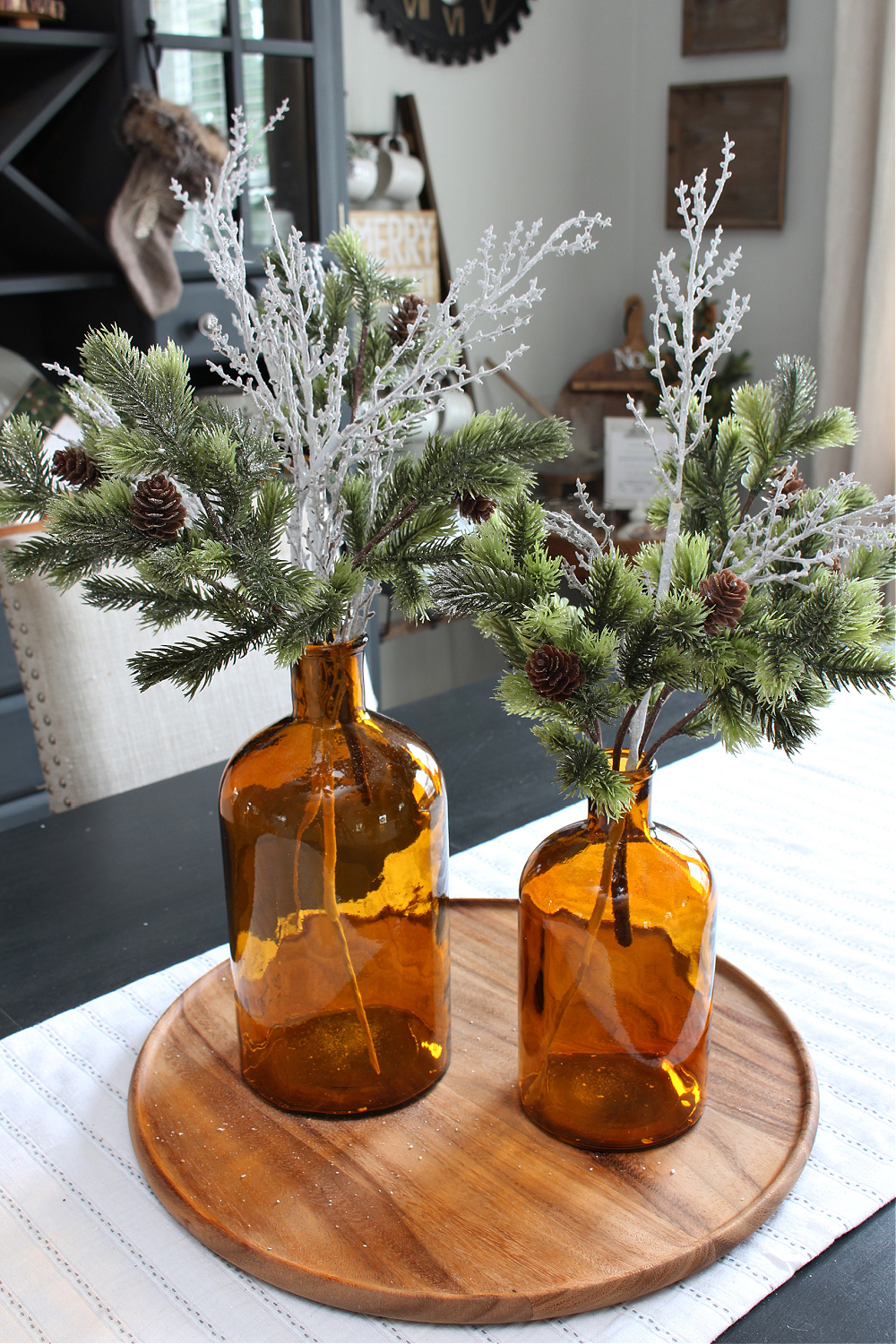 Pretty DIY Christmas centerpiece with amber bottles and greenery.