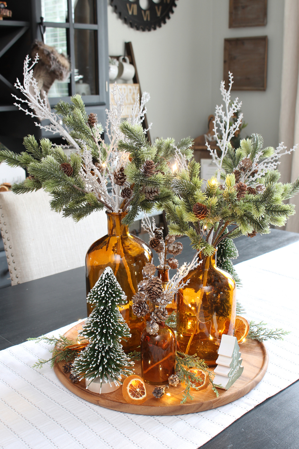 Pretty lighted Christmas centerpiece with amber glass bottles and greenery.