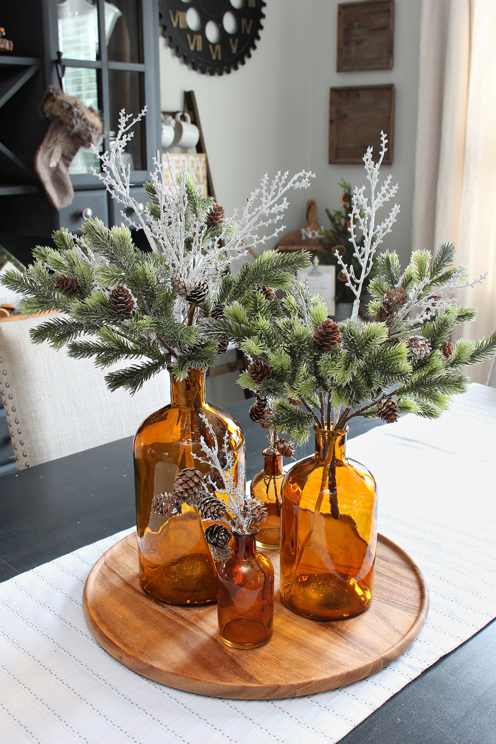 Pretty Christmas centerpiece with amber glass bottled and greenery.