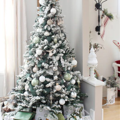 Flocked Christmas tree decorated with green, white, and metallics.