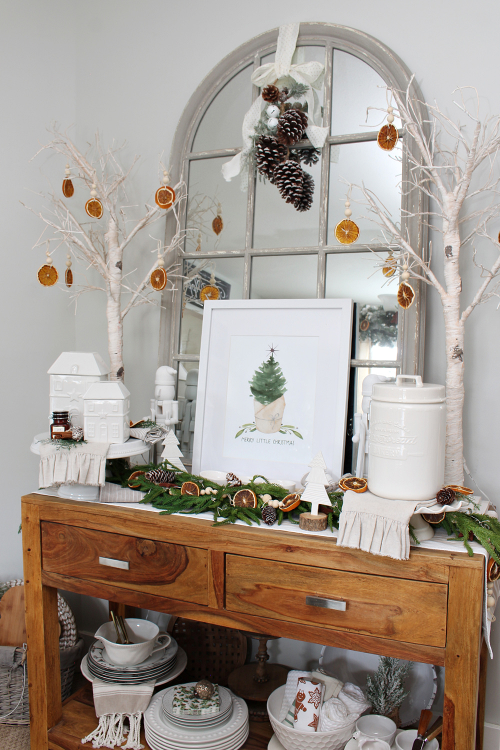 Dining room side board decorated for Christmas with greens and dried oranges.