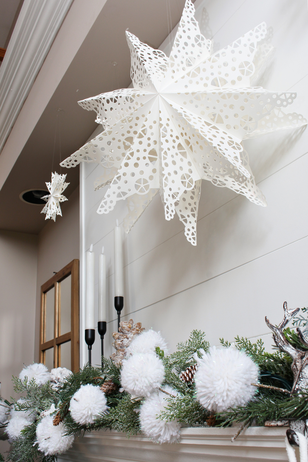 Winter wonderland Christmas mantel with pom pom snowball garland and paper snowflakes.