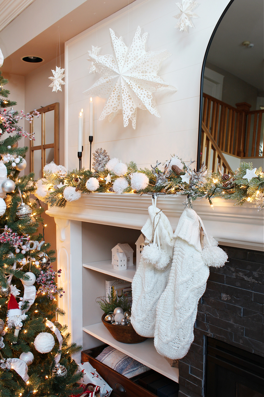 Christmas mantel with paper snowflakes, snowballs, and white stockings.