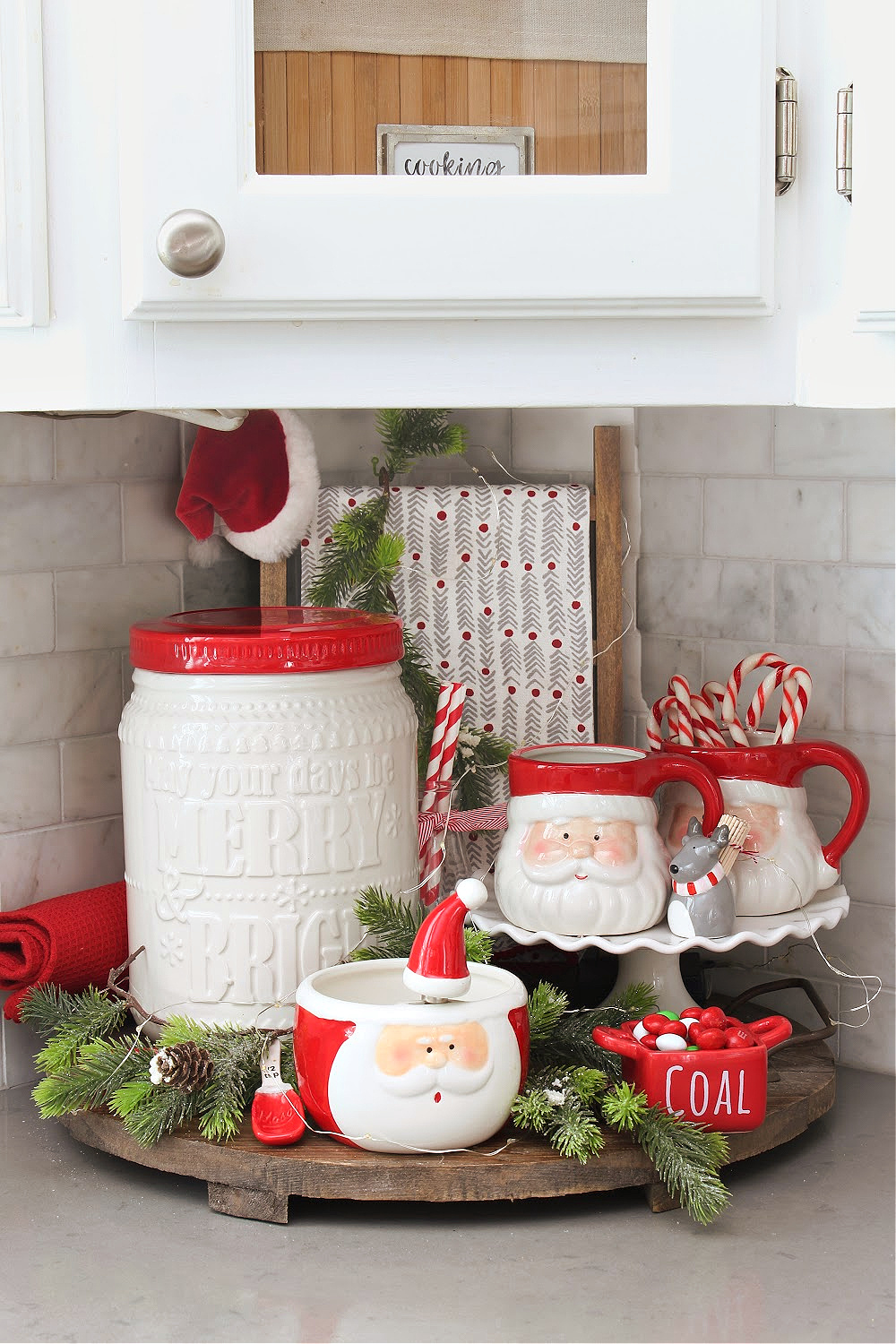 Red and white Christmas kitchen display with Santa mugs.