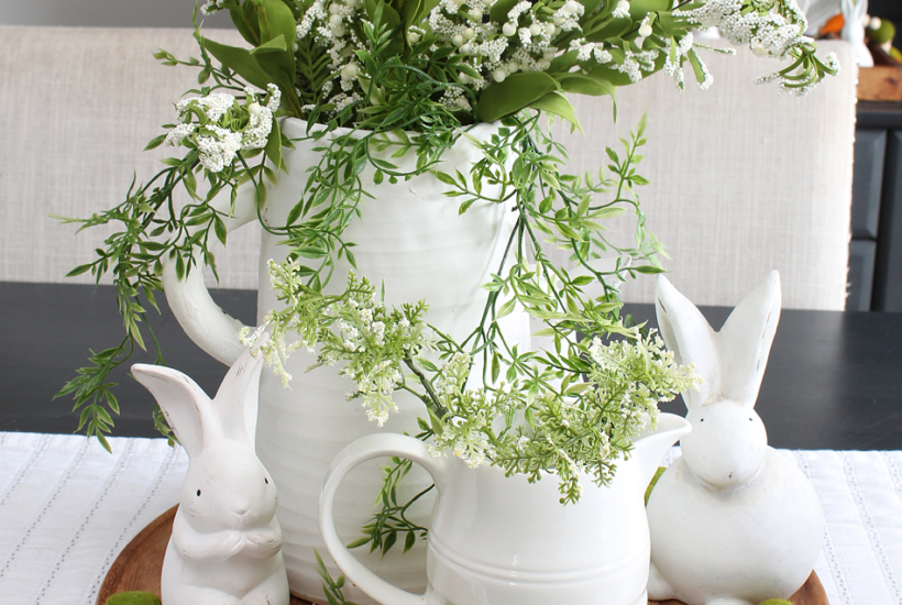 Simple spring centerpiece with white vases, greenery, and white bunnies.