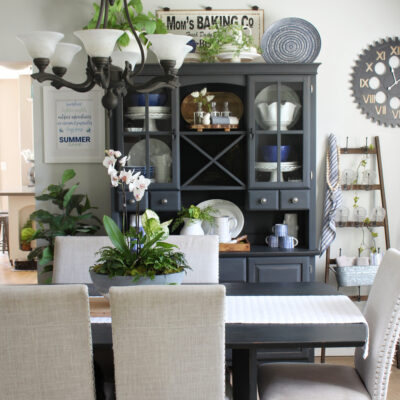 Black hutch and dining room table decorated for summer with blues and greens.