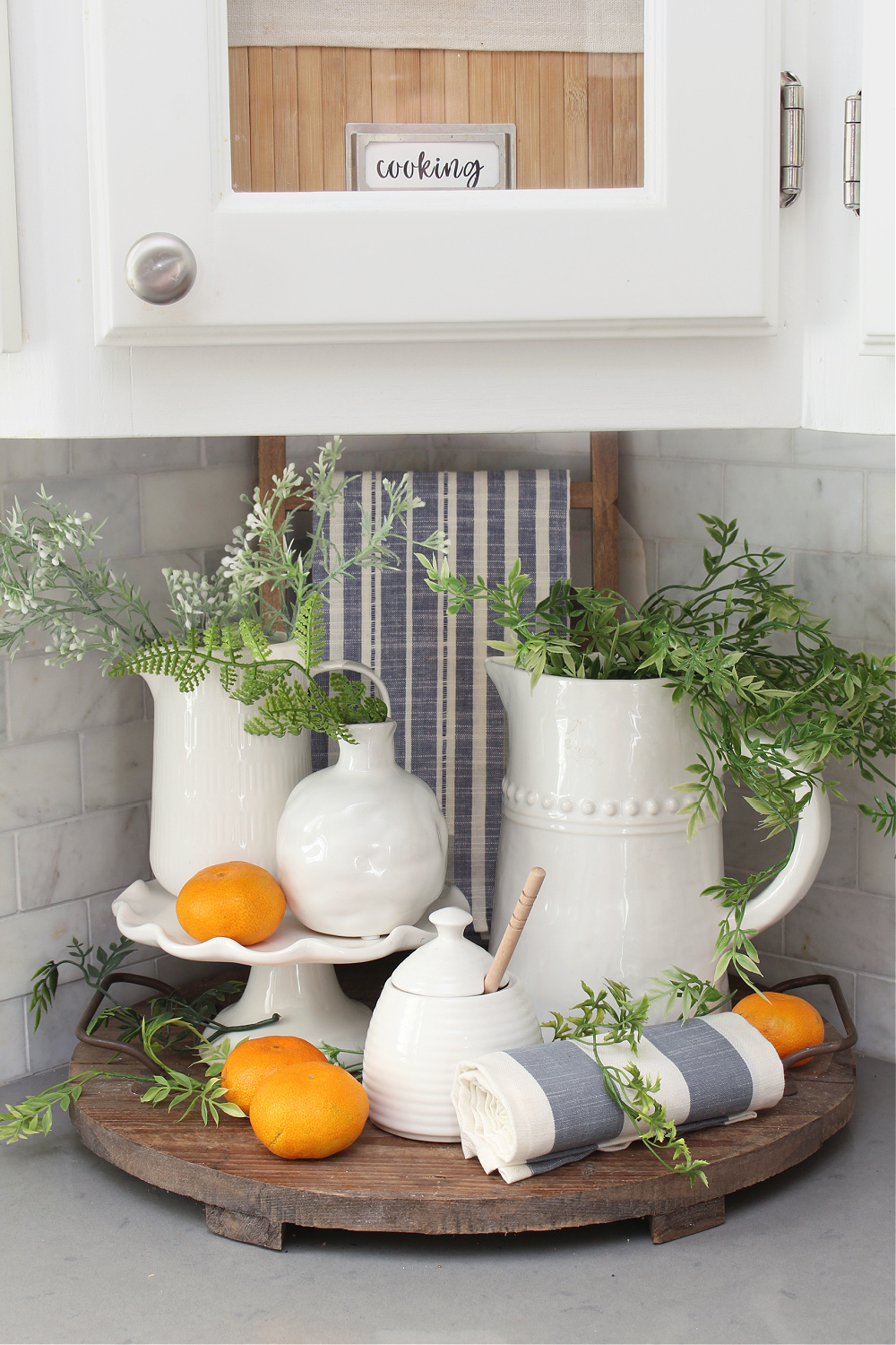 A summer vignette of a kitchen with white pottery and pops of blue and orange.