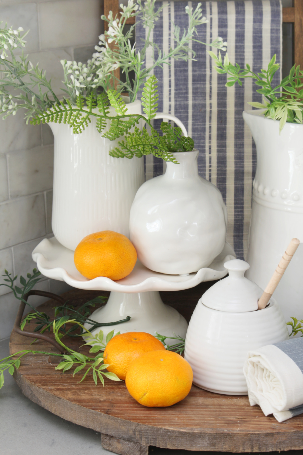 A summer vignette of a kitchen with white pottery and pops of blue and orange.