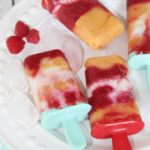 Raspberry peach yogurt popsicles on a plate with ice.
