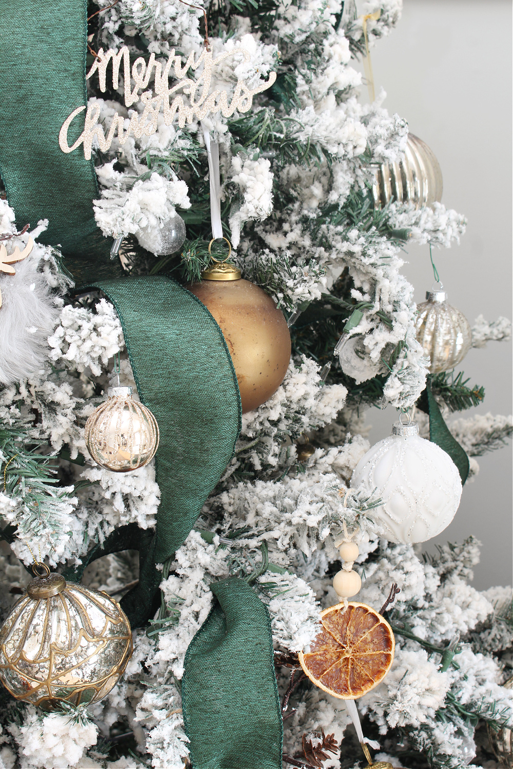A Christmas tree decorated with metallic and dry oranges.