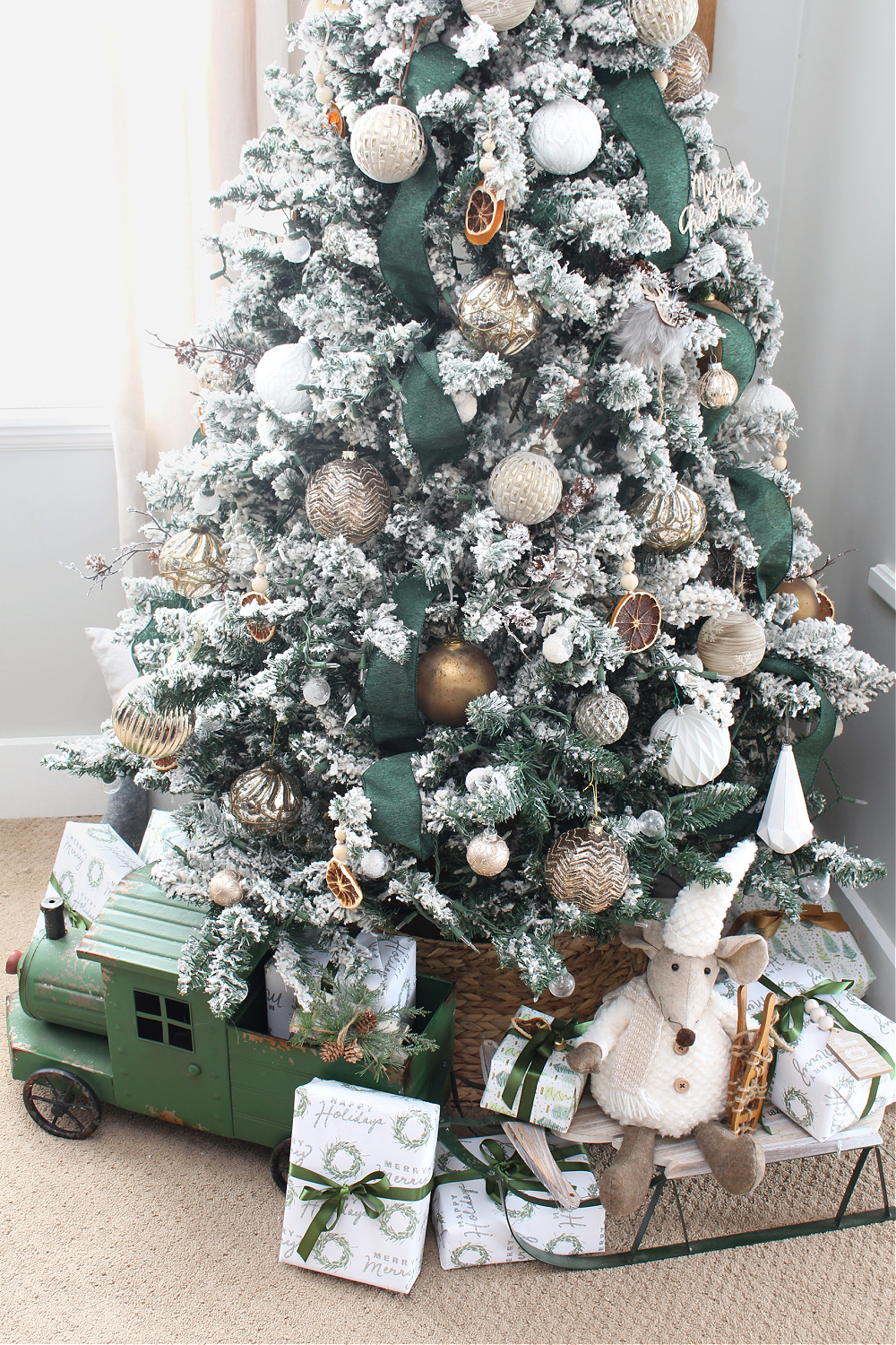 Christmas tree decorated with green ribbon and metallic ornaments.
