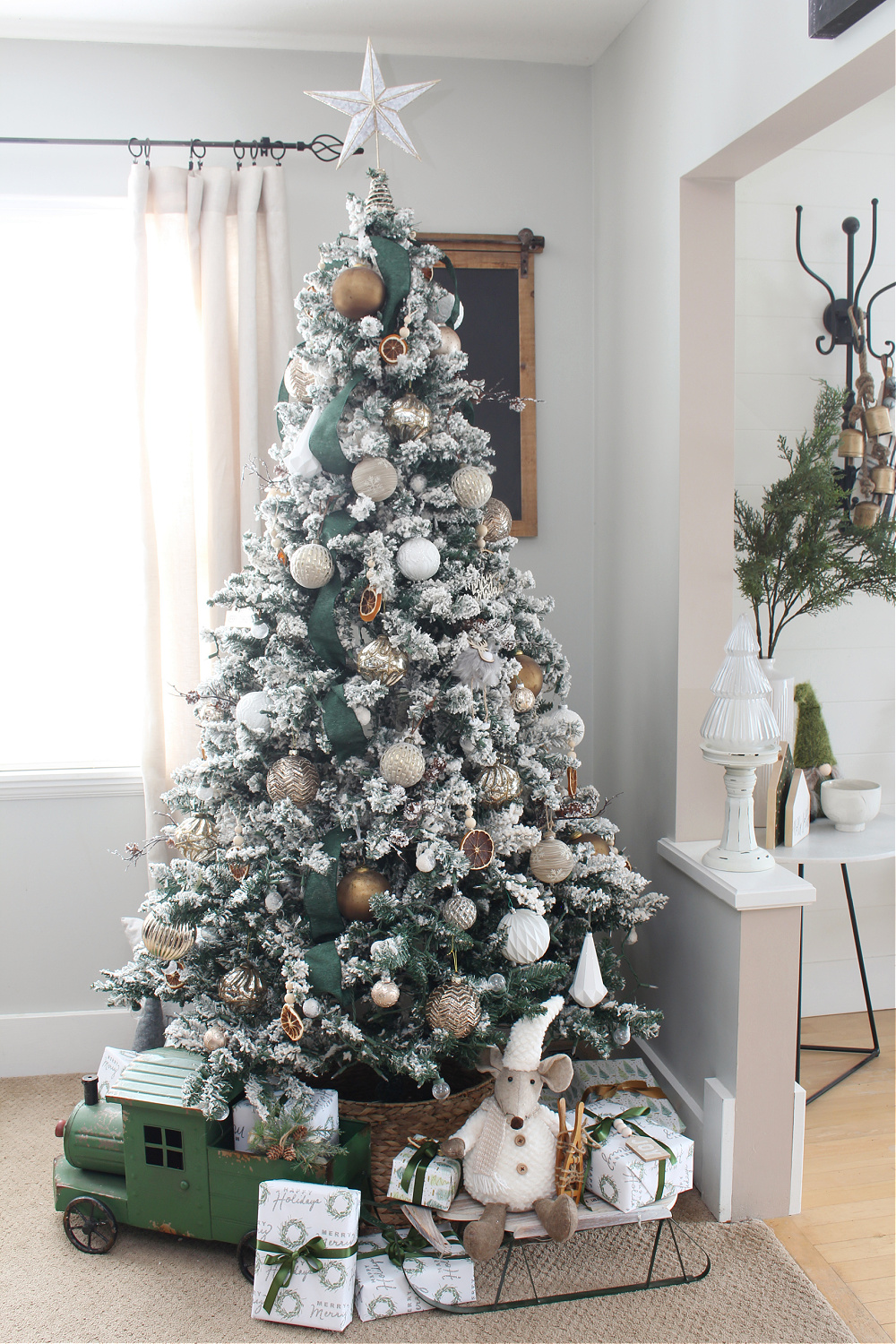 Christmas tree decorated with green ribbon and metallic ornaments.
