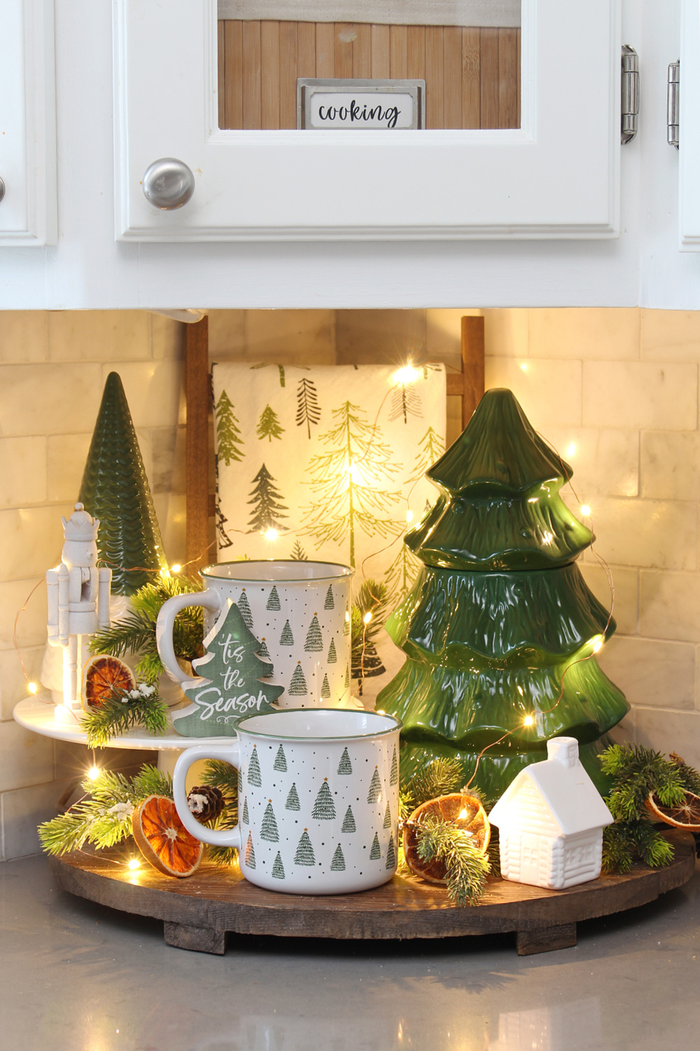 White and green Christmas vignette with trees in a kitchen.