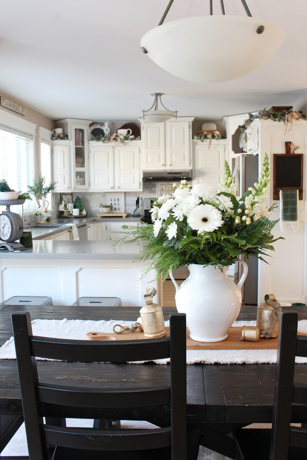 A white kitchen decorated for Christmas in green and white.