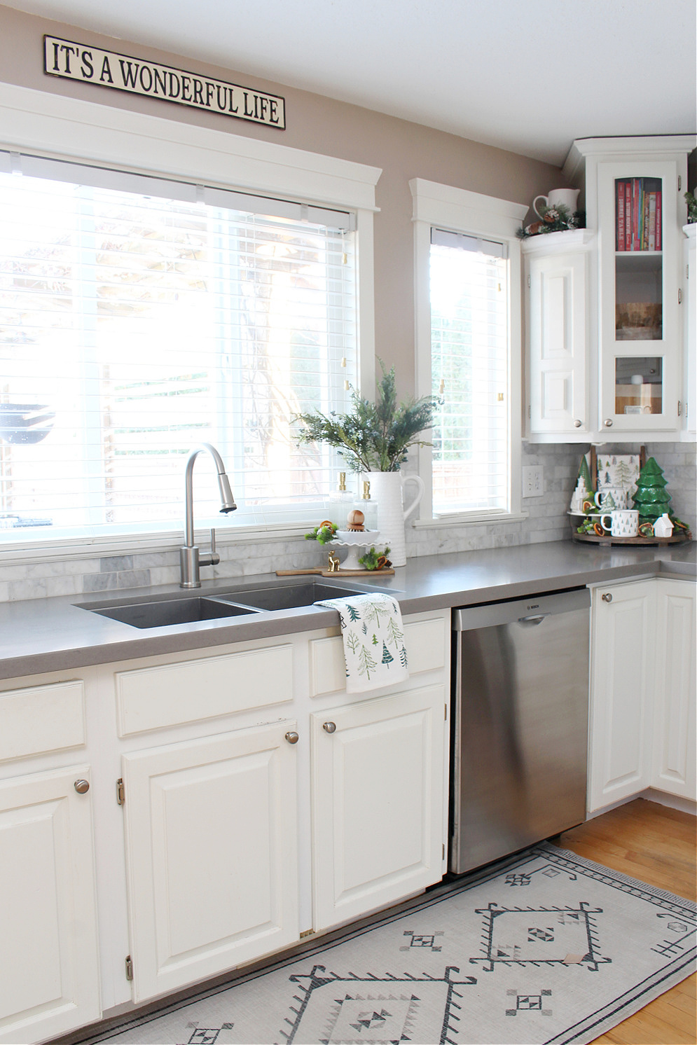 A white kitchen decorated for Christmas with green accent colors.