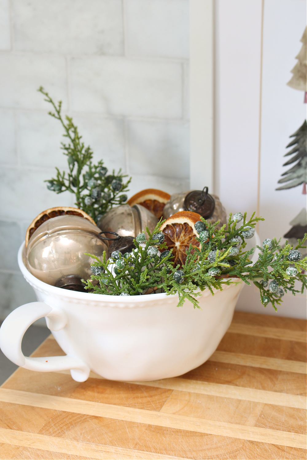 Greenery, ornaments, and dried oranges in a kitchen bowl.
