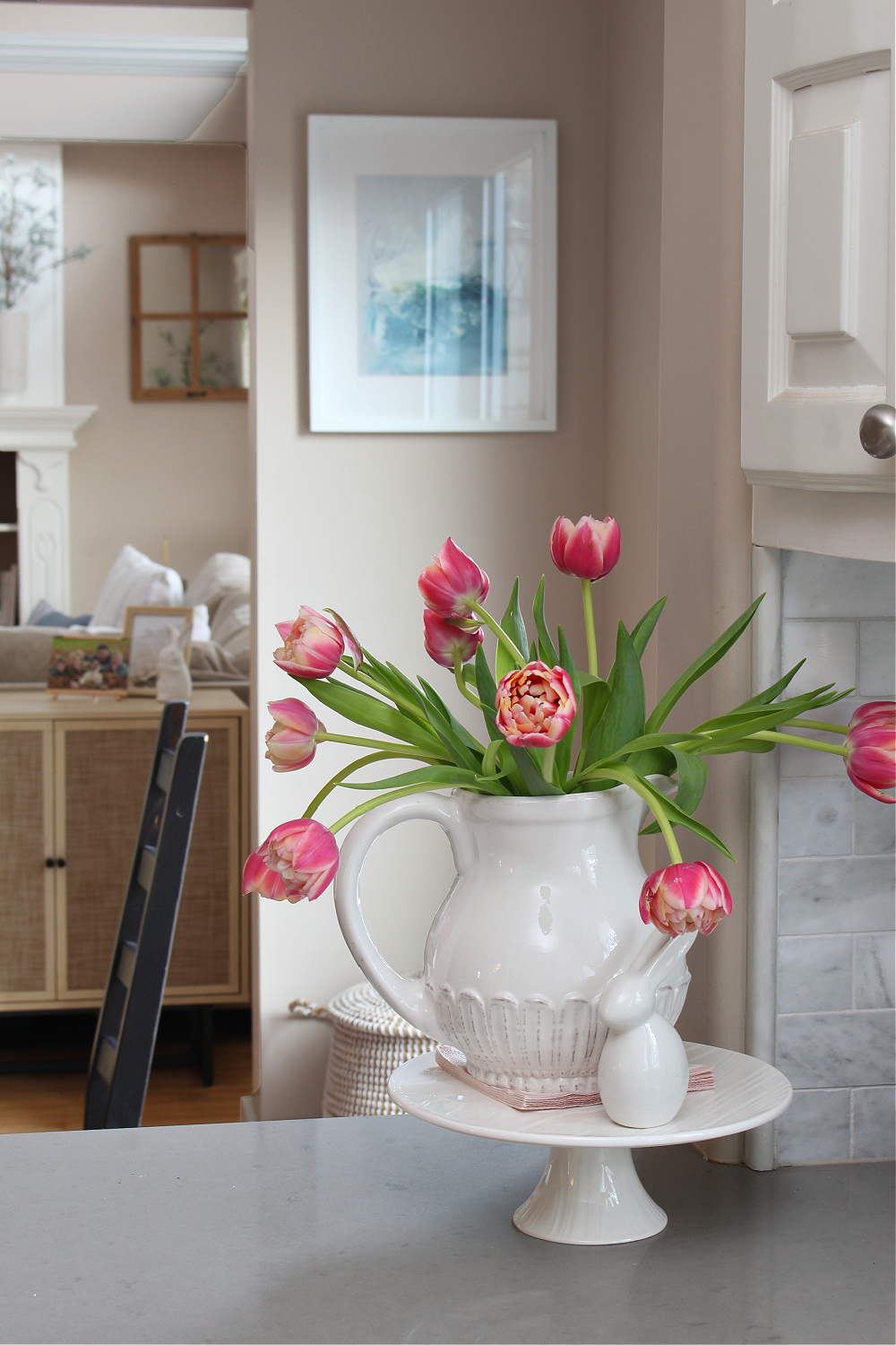 White vase with tulips in a white kitchen decorated for spring.