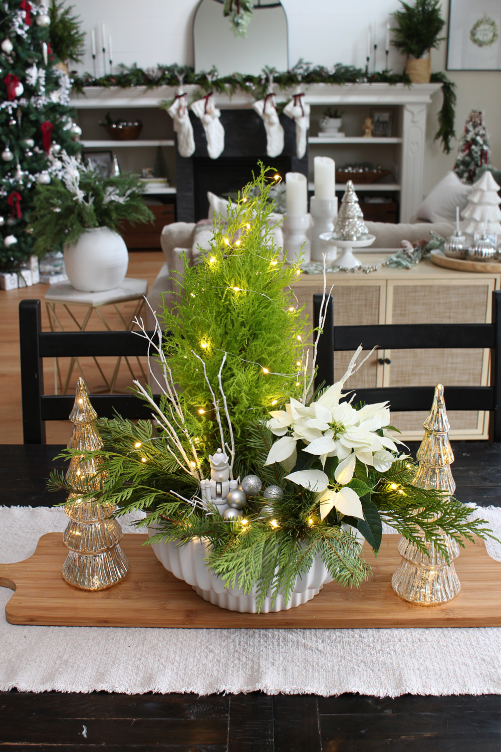 Fresh greenery Christmas centerpiece using a lemon cypress and poinsettia. Embellished with twinkle lights and a nutcracker. #Christmascenterpiece #centerpieceideas #Christmasdecor #Christmascrafts #ChristmasDIY #twinklelights